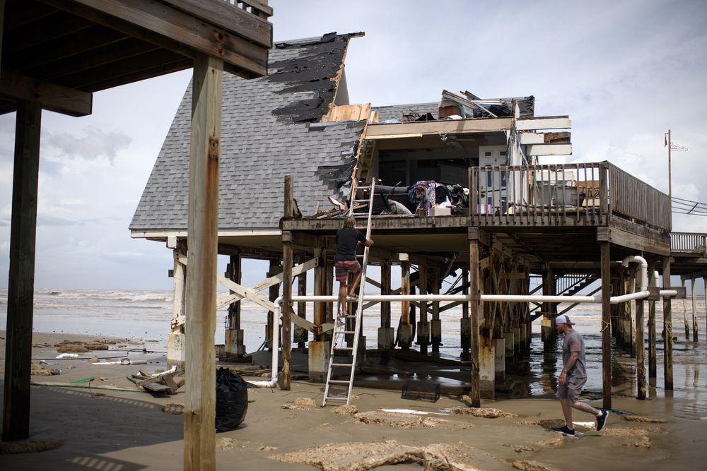 Mike Isbell (centro) sube una escalera para observar los restos de su casa que fue destruida en Surfside Beach, Texas, el 8 de julio de 2024, después de que el huracán Beryl tocara tierra.