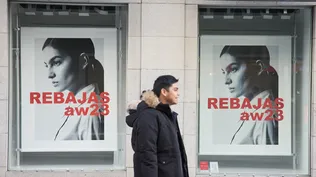Una hombre camina delante de un escaparate anunciando las rebajas, en el centro de Madrid.