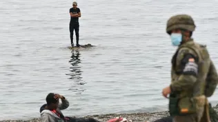 Archivo.- Un migrante que llegó a nado desde Marruecos al enclave español de Ceuta descansa en una roca antes de llegar a la playa donde le espera el Ejército español