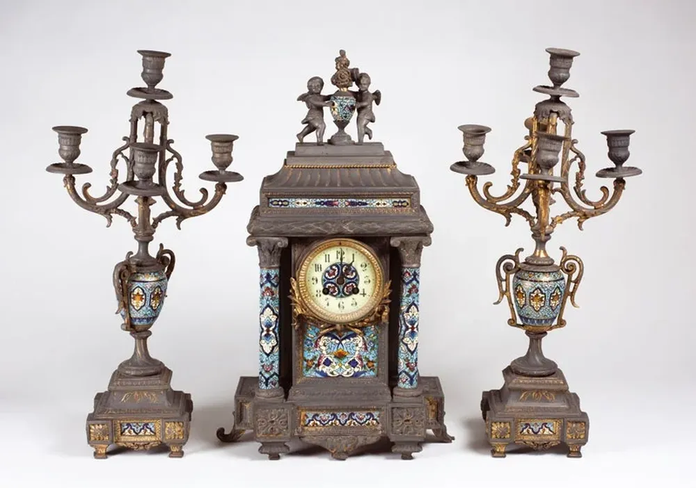 Garniture francesa, en petit bronce y cloisonne, en variado colorido, con un reloj de cuerpo rectangular, con esfera esmaltada de números arábigos y cristal