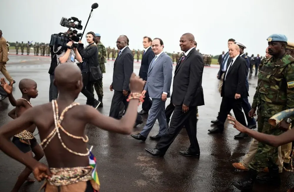 El presidente Hollande en la República Centro Africana mirando a los bailarines que lo reciben.