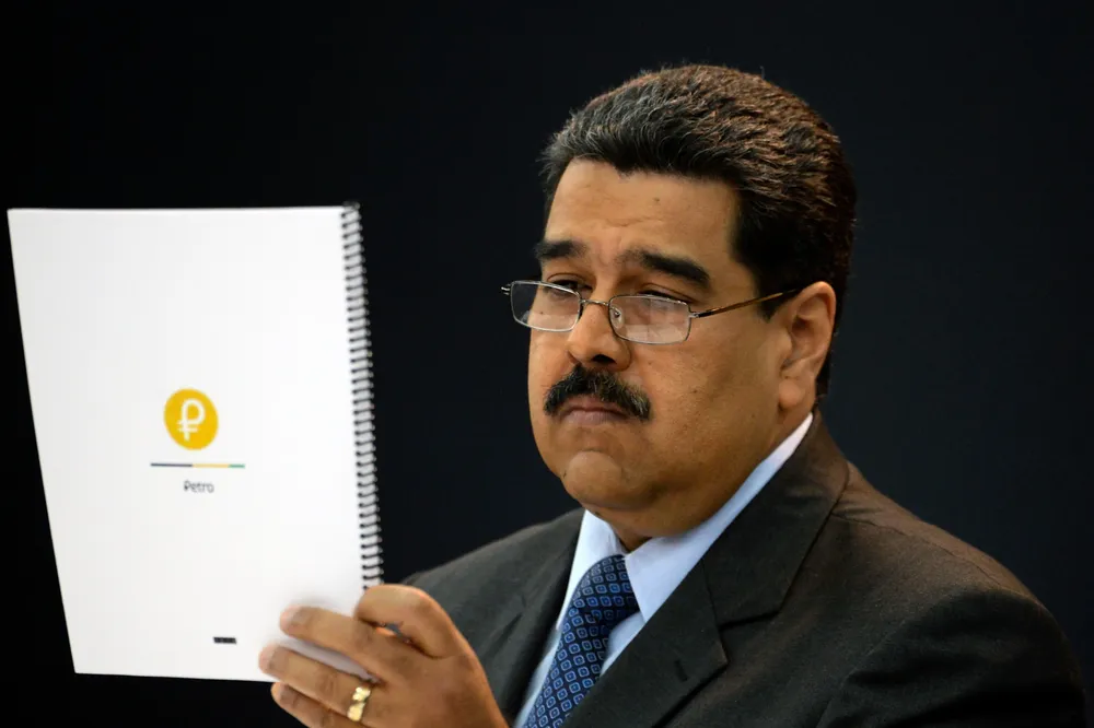Venezuelas President Nicolas Maduro looks at a document during a press conference to launch to the market a new oil-backed cryptocurrency called Petro, at the Miraflores Presidential Palace in Caracas, on February 20, 2018.  Venezuela formally launched its new oil-backed cryptocurrency on Tuesday in an unconventional bid to haul itself out of a deepening economic crisis. The leftist Caracas government put 38.4 million units of the worlds first state-backed digital currency, the Petro, on private pre-sale from the early hours. A total of 100 million Petros will go on sale, with an initial value set at $60, based on the price of a barrel of Venezuelan crude in mid-January.           / AFP / FEDERICO PARRA