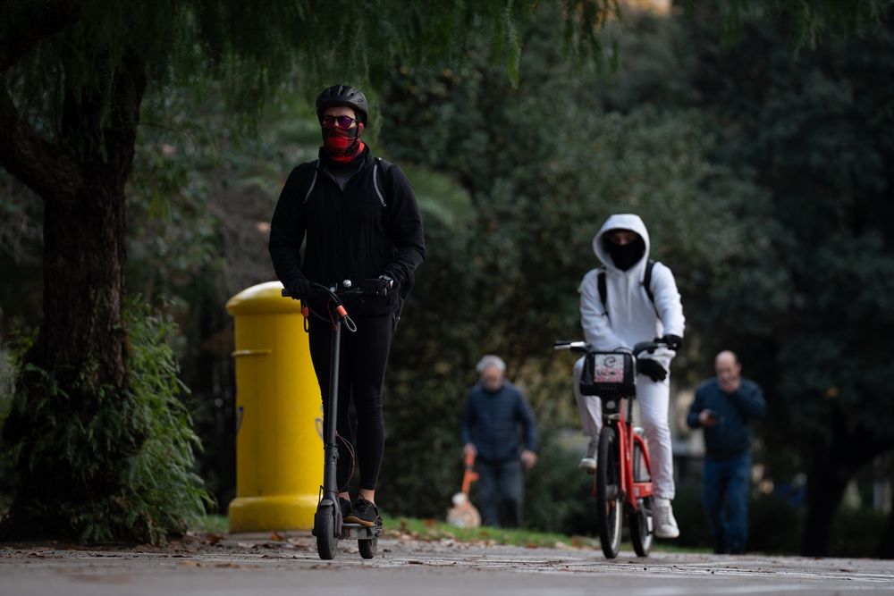 Una persona en patinete y otra en bicicleta pasean por Barcelona