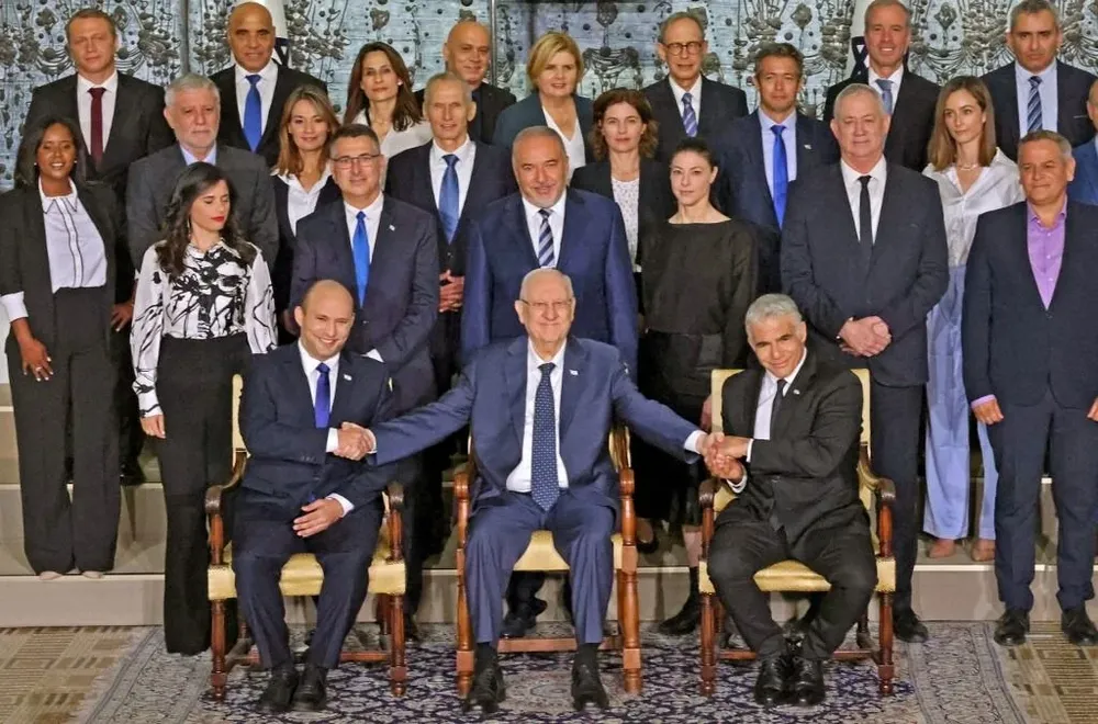 El presidente israelí saliente Reuvin Rivlin, flanqueado por el primer ministro Naftali Bennett y el primer ministro suplente y ministro de Relaciones Exteriores Yair Lapid durante una foto con el nuevo gobierno de coalición, en la residencia del presidente en Jerusalén, el 14 de junio de 2021