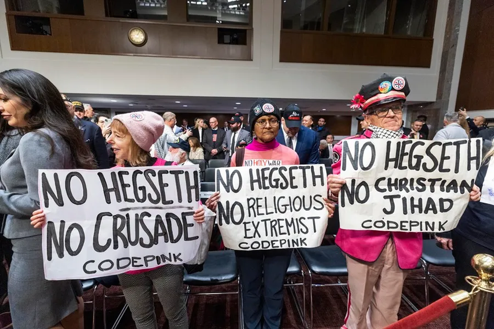 Manifestantes esperan la llegada del candidato a Secretario de Defensa Pete Hegseth a su audiencia de confirmación ante el Comité de las Fuerzas Armadas del Senado.