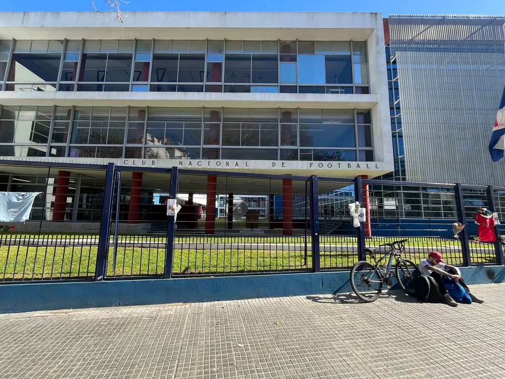Un hincha de Nacional recostado contra un muro de la sede del club, homenajeando a Juan Izquierdo