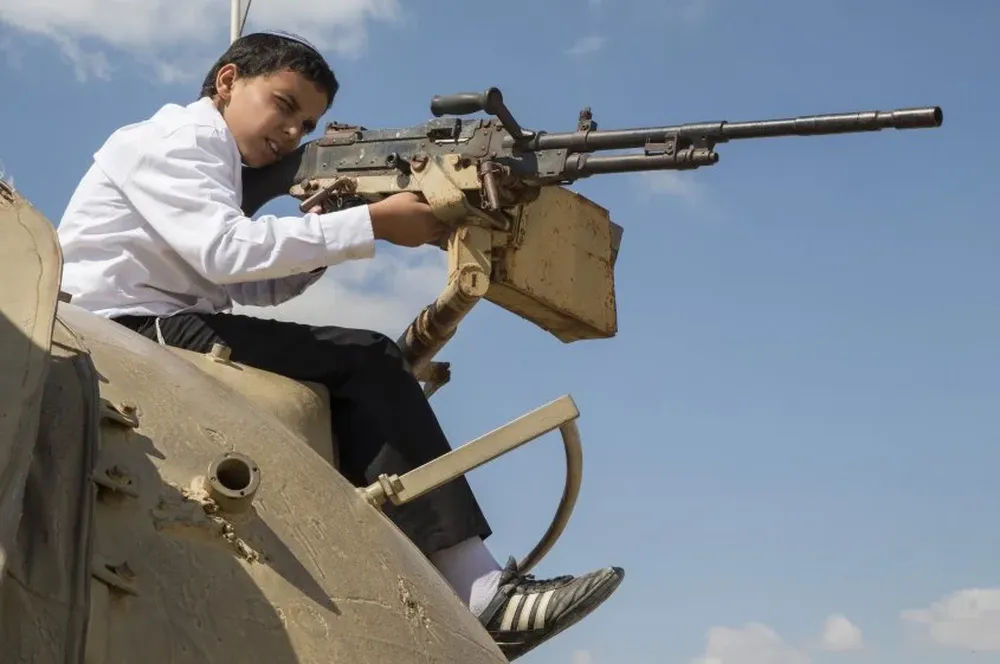 Un niño apunta con una pistola sin funcionar en el memorial a los soldados caidos en guerra en Israel.