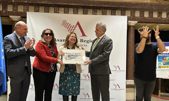La presidenta de la Asamblea Regional, Visitación Martínez, presenta el cupón especial de la ONCE dedicado a la reforma del artículo 49 de la Constitución que ha permitido sustituir el término ‘disminuido’ por el de ‘personas con discapacidad’