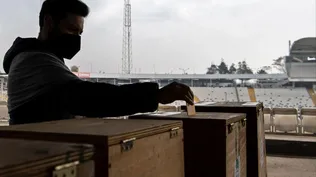 Un hombre emite su voto durante las elecciones para elegir alcaldes, concejales y una comisión para reescribir la constitución en un colegio electoral instalado en el Estadio Monumental de Santiago.