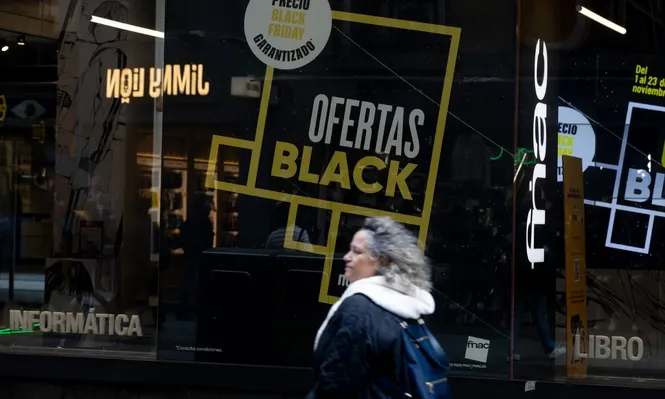 Una persona pasa por delante de una tienda que anuncia un cartel publicitario del ‘Black Friday’.