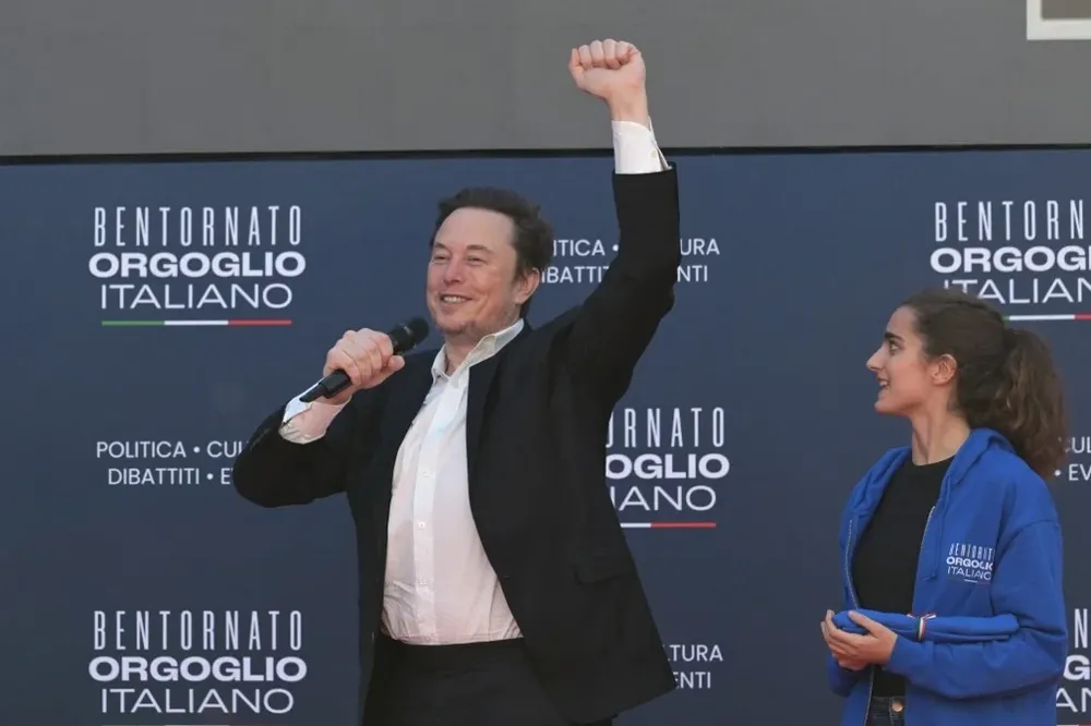 Elon Musk, dueño de X, levanta el puño en un encuentro organizado por militantes de la derechista formación Hermanos de Italia que tiene a Giorgia Meloni como primera ministra del país.