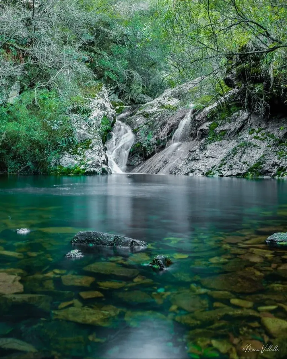 Cascadas de agua cristalina en una quebrada de monte nativo junto a paredones de piedra.