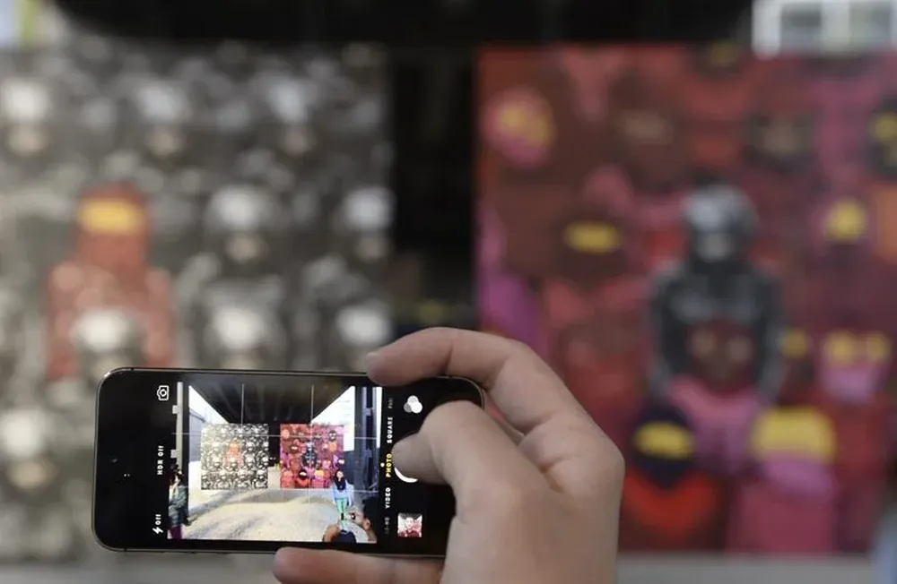 Un hombre toma una foto de una obra de arte callejera con su celular, en Nueva York