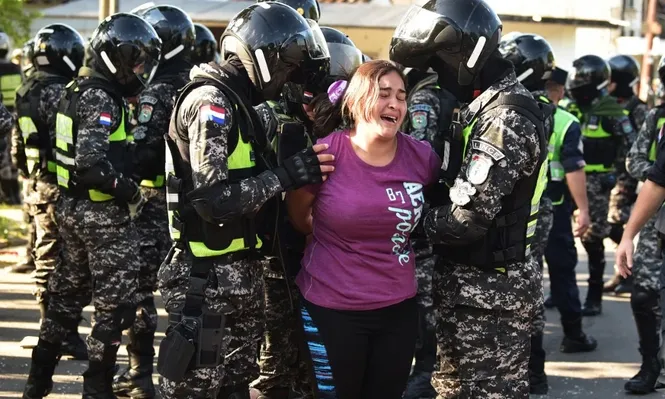 Miembros de las fuerzas de seguridad paraguayas controlan a una familiar de uno de los presos en la cárcel de Tacambú.