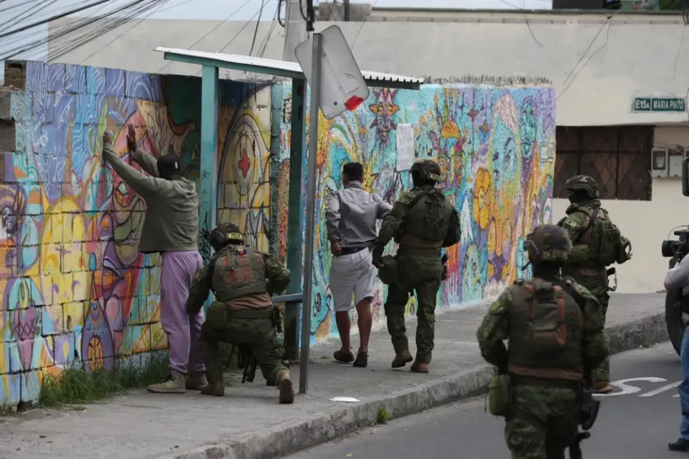 Una compañía de soldados de Ecuador requisa a dos hombres en Quito.