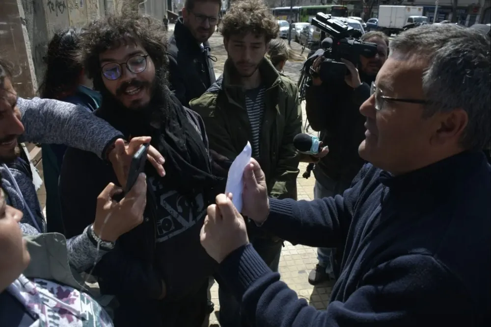 El director de Convivencia y Seguridad Ciudadana, Santiago González, le muestra el pedido de desalojo a un estudiante para que le saque una foto