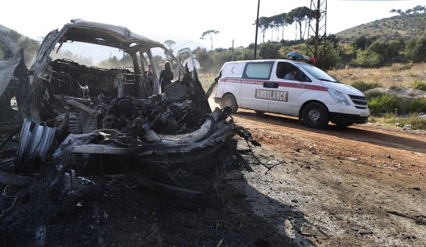 Una ambulancia pasa junto a un vehículo quemado en la localidad de Masyaf, Siria.