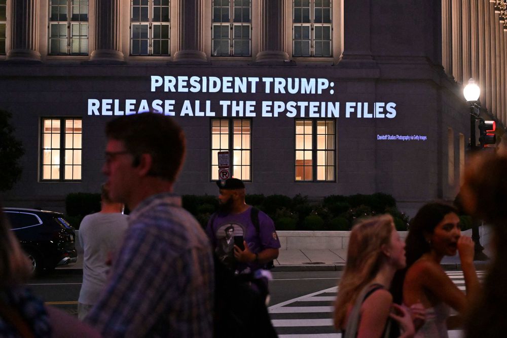 Donald Trump inició una demanda: la gente pasa mientras un mensaje que pide al presidente de EEUU que publique todos los archivos relacionados con Jeffrey Epstein se proyecta en el edificio de la Cámara de Comercio de EEUU frente a la Casa Blanca en Washington, DC, el 18 de julio de 2025.