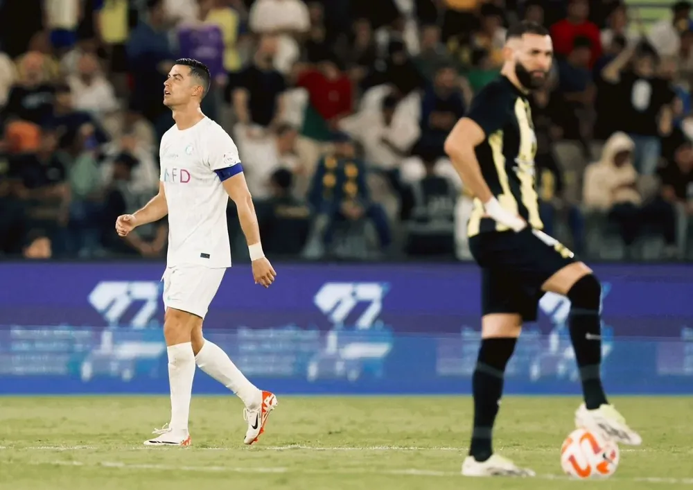 Karim Benzema con la pelota bajo el pie y detrás Cristiano Ronaldo