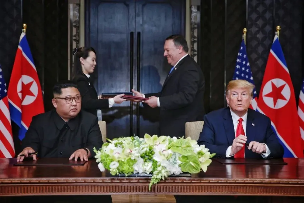 This handout photo taken on June 12, 2018 and released by The Straits Times shows US President Donald Trump (R) and North Koreas leader Kim Jong Un (L) looking on as documents are exchanged between US Secretary of State Mike Pompeo (2nd R) and the North Korean leaders sister Kim Yo Jong (2nd L) at a signing ceremony during their historic US-North Korea summit, at the Capella Hotel on Sentosa island in Singapore. Donald Trump and Kim Jong Un became on June 12 the first sitting US and North Korean leaders to meet, shake hands and negotiate to end a decades-old nuclear stand-off.Kevin LIM / THE STRAITS TIMES / AFP
