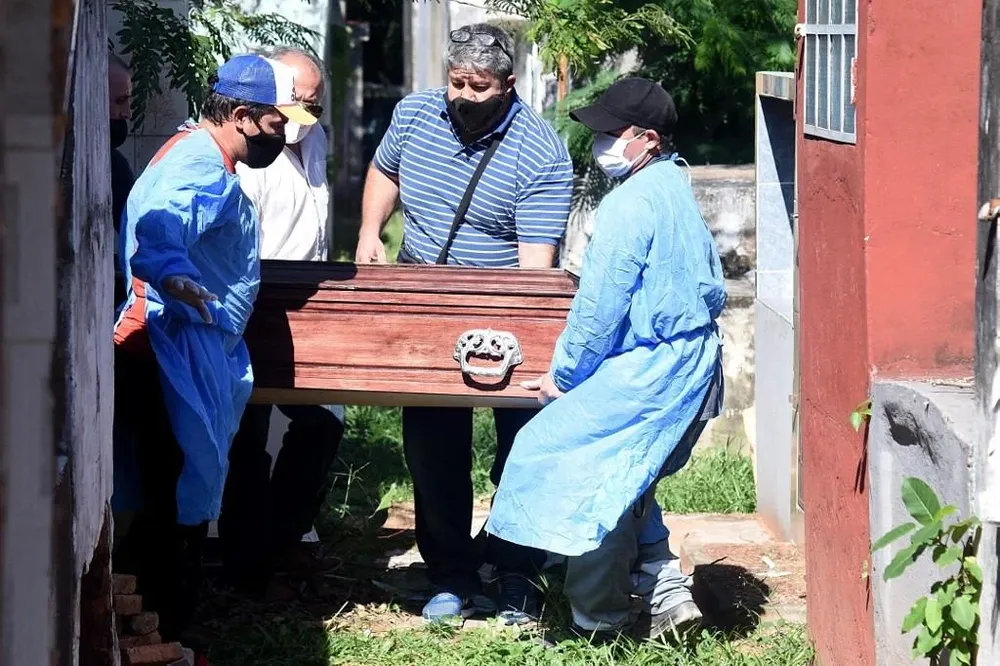 Trabajadores cargan el ataúd de una víctima del covid-19 en el cementerio Cementerio del Sur de Asunción