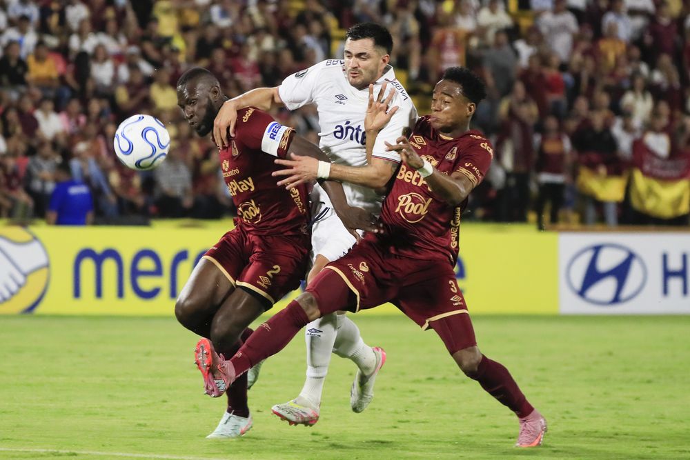 Anderson Angulo y Jan Carlos Angulo de Deportes Tolima disputan el balón con Maximiliano Gómez de Nacional por la Copa Libertadores