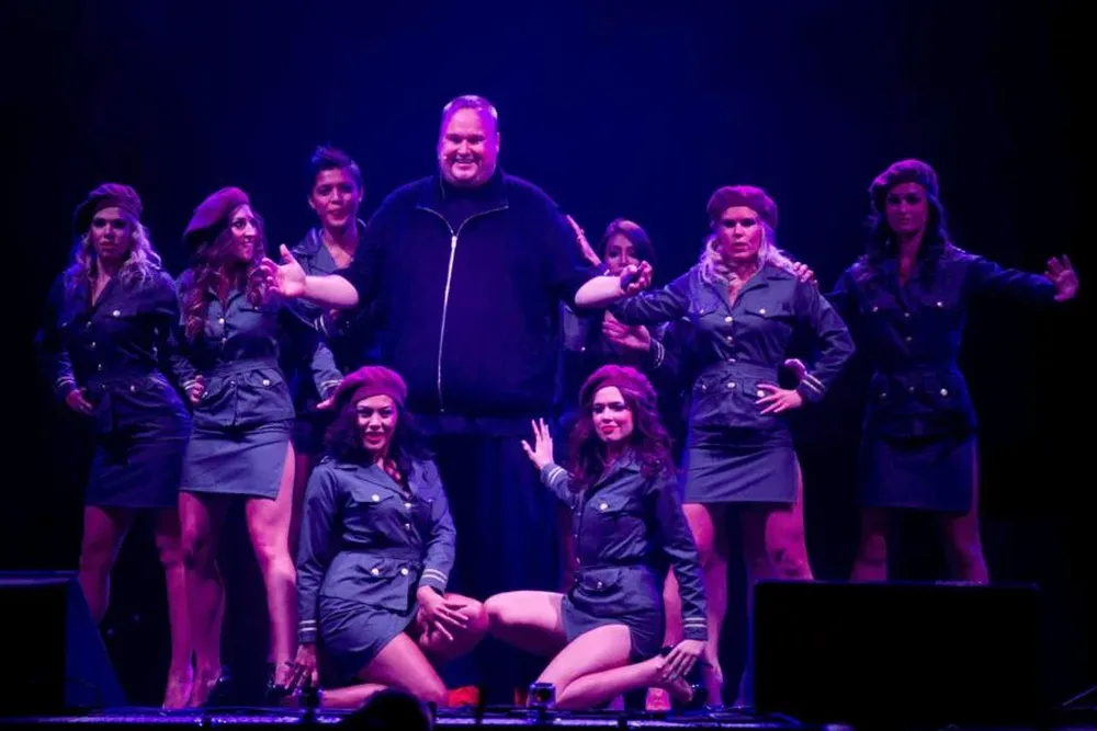 Kim Dotcom junto a las policías-bailarinas en el escenario montado en el jardín de su mansión durante la presentación de Mega