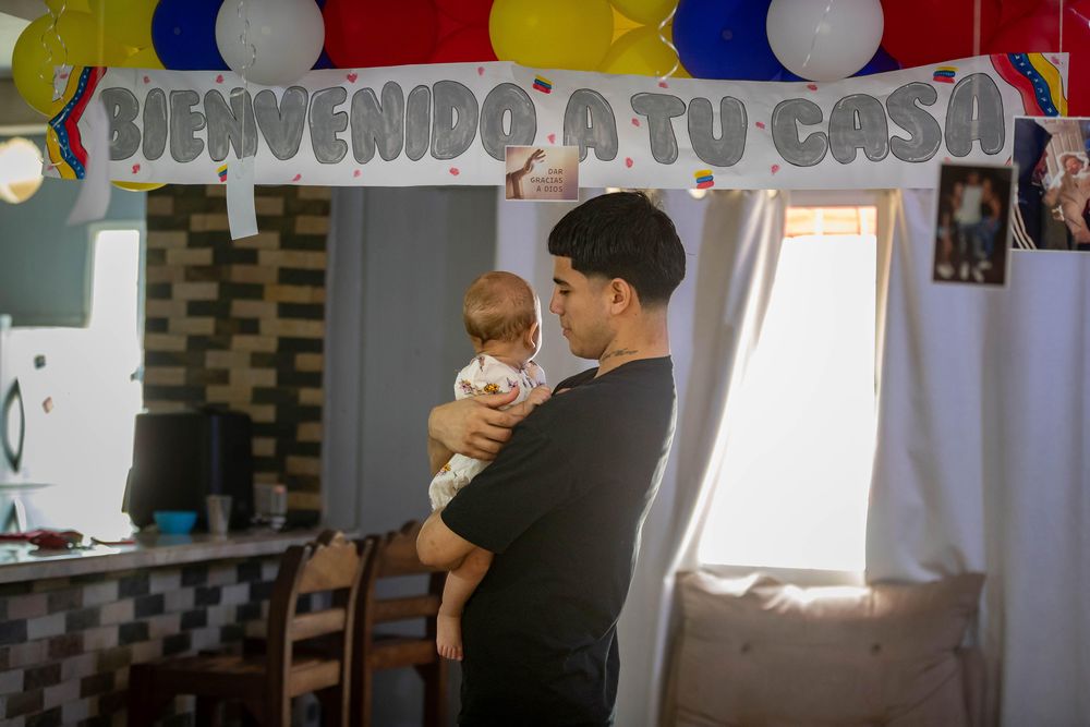 Joén Suárez sostiene en brazos a su hija desde la casas de su familia a las afueras de Caracas.