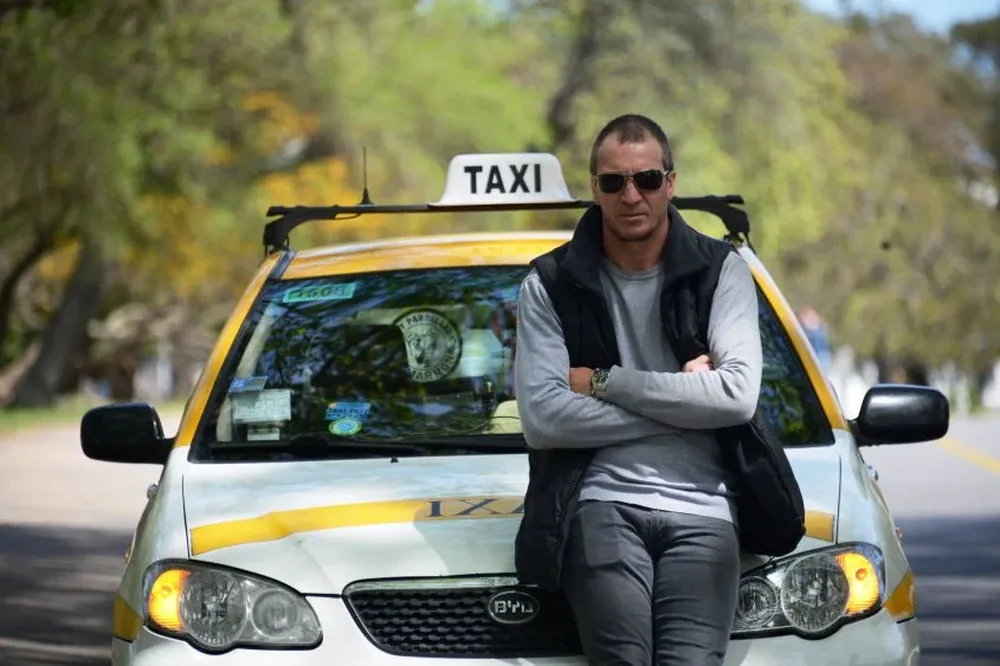 Carlos Macchi maneja un taxi mientras planifica su futuro como entrenador.