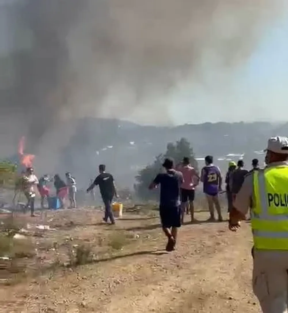 Captura de pantalla del video donde se ven algunas llamas del incendio en Pueblo Obrero y vecinos luchando para extinguirlas