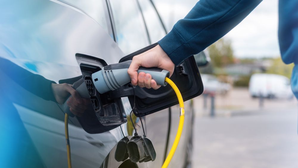 man-plugging-charger-into-electric-car-charge-station