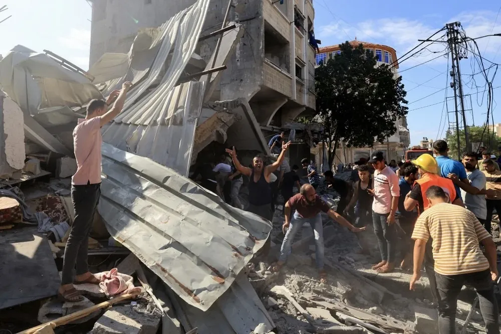 Palestinos intentan rescatar cuerpos y víctimas entre los escombros de un edificio destruido en el sur de Gaza.