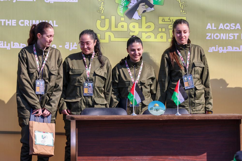 Cuatro rehenes israel&iacute;es (de izquierda a derecha: Naama Levy, Liri Albag, Daniella Gilboa y Karina Ariev) saludan desde un escenario antes de que los combatientes de Hamas las entreguen a un equipo de la Cruz Roja en la ciudad de Gaza el 25 de enero de 2025.