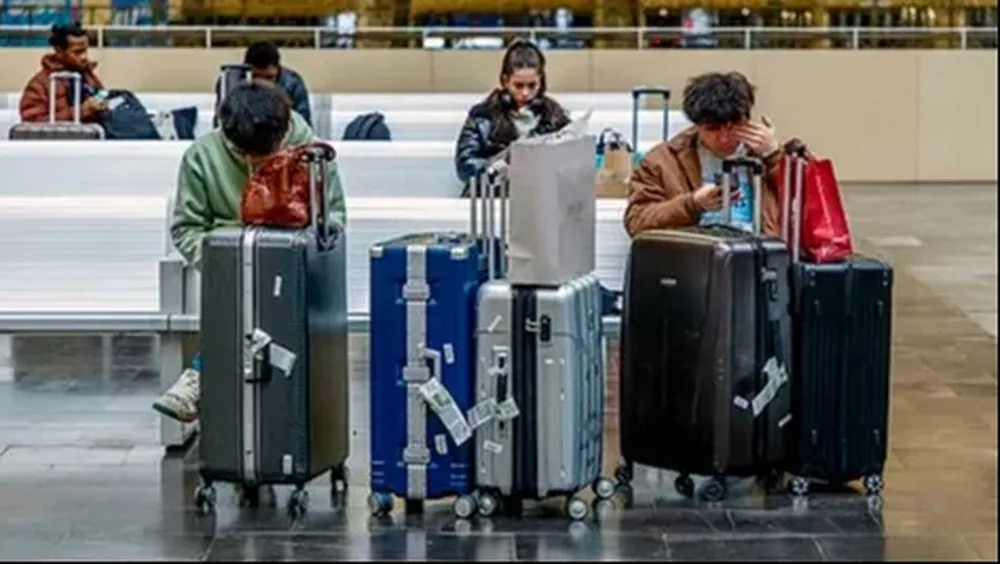 Varias personas esperan junto con el equipaje.