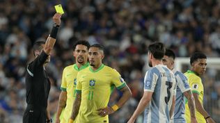 El árbitro colombiano Andrés Rojas le muestra la tarjeta amarilla a Nicolás Tagliafico de Argentina y a Raphinha de Brasil por las Eliminatorias