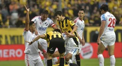 Diego Polenta levanta su mano avisándole a la sanidad de Peñarol que ingrese luego de ver al Canario Álvarez desvanecido en el suelo