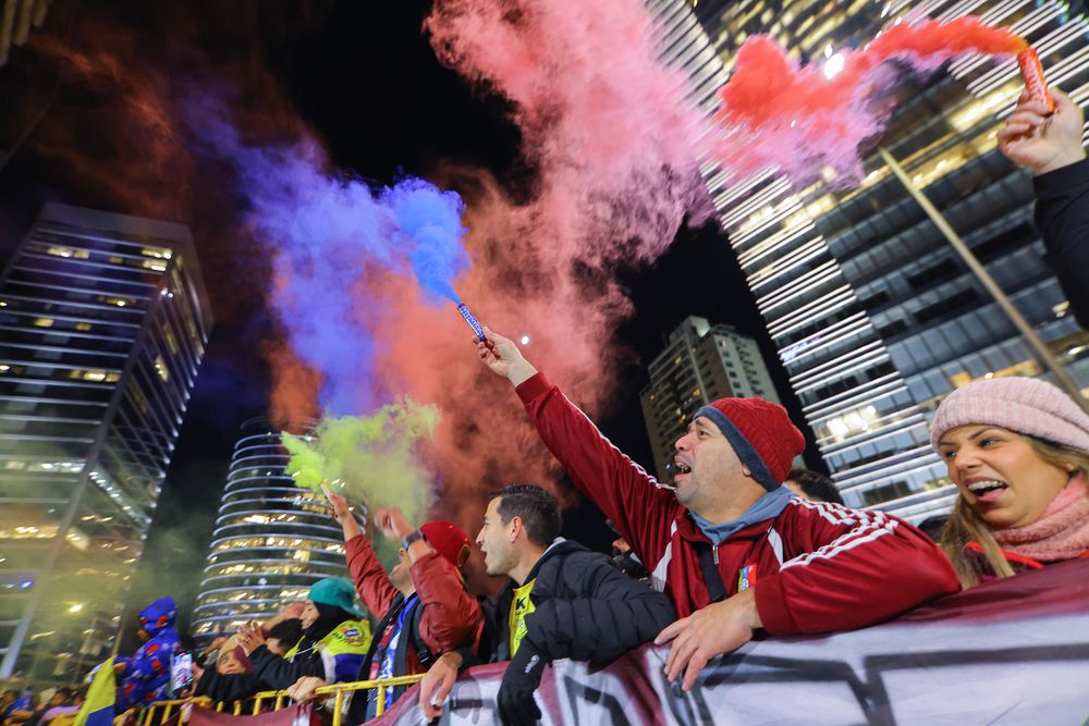 Hinchas sostienen bengalas durante el recibimiento a la selección de fútbol de Venezuela este lunes, frente al Hotel Hilton Garden en Montevideo