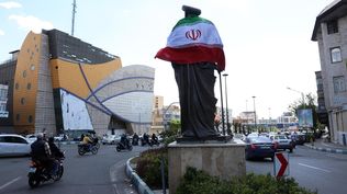 Una bandera iraní envuelve una estatua en Teherán tras el anuncio de la tregua