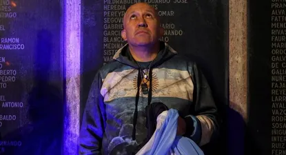 Un hombre sostiene la bandera argentina en el monumento que está en Buenos Aires a los caídos en la guerra