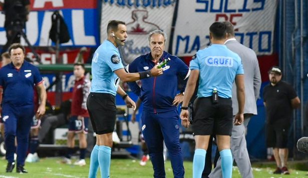 Esteban Ostojich entrega al encargado de seguridad una petaca que cayó desde la tribuna