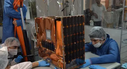 Empleados de Satellogic trabajando sobre un satélite.