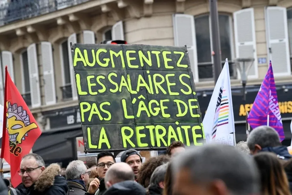 Los manifestantes sostienen una pancarta que dice Aumentar los salarios, no la edad de jubilación durante el cuarto día de las manifestaciones contra la reforma de pensiones.