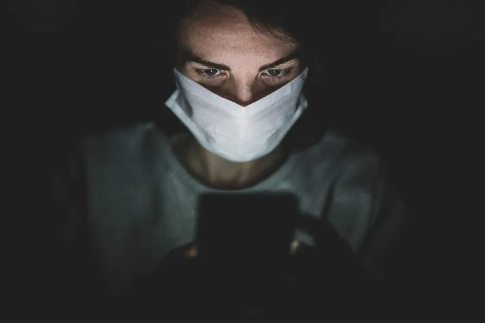man-wearing-face-mask-using-his-phone-in-the-dark-4031909.webp