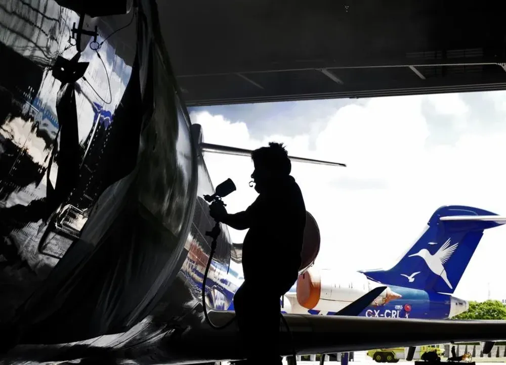 Funcionarios de la exPluna pintan de blanco el espacio donde se ubicaba el logo de la empresa en los aviones que serán transportados a Canadá