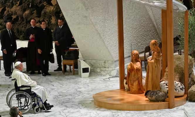 El Papa Francisco reza frente al Belén donde el niño Jesús está envuelto en un tradicional pañuelo palestino