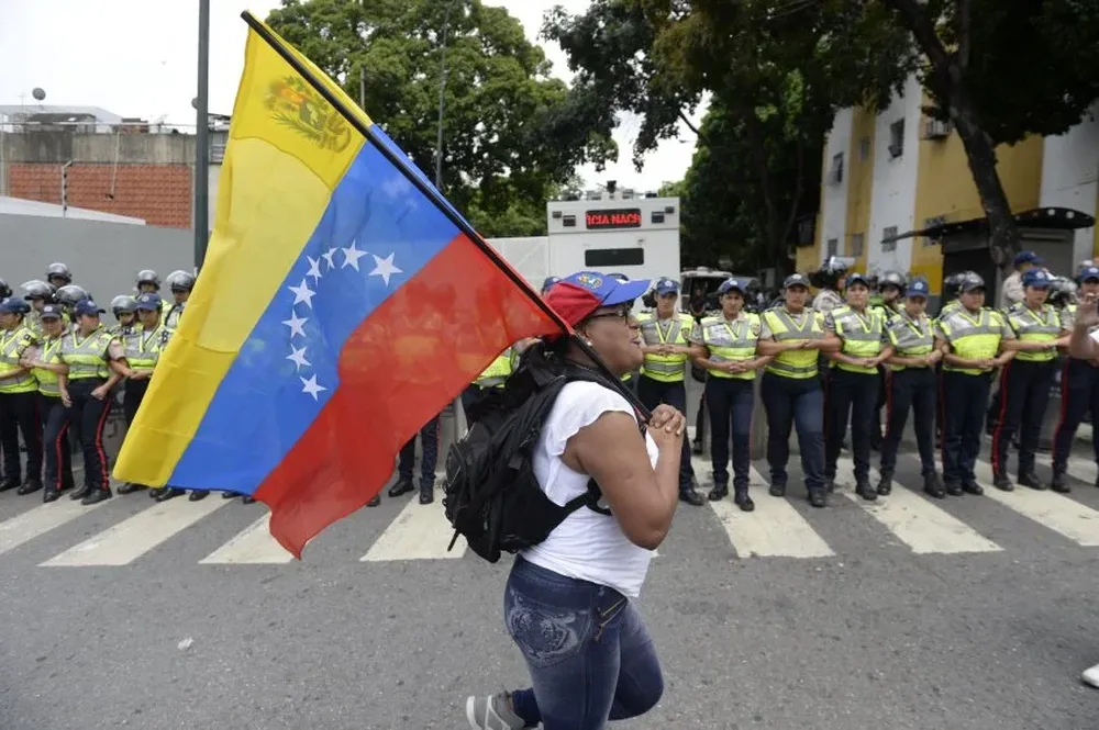 Una manifestante pasa con la bandera de Venezuela frente al cordón policial que dispuso el gobierno.
