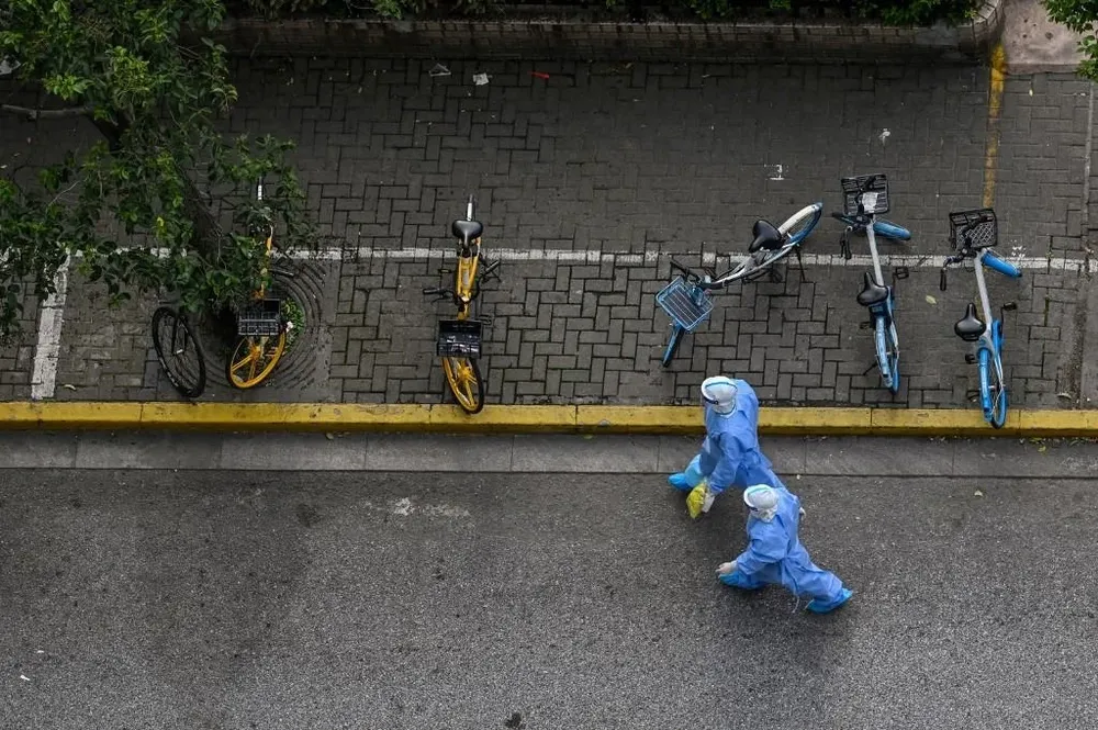 Trabajadores de la salud recorren una zona confinada de Shanghai