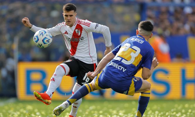 Lautaro Blanco, de Boca, disputa un balón con Fabricio Bustos de River