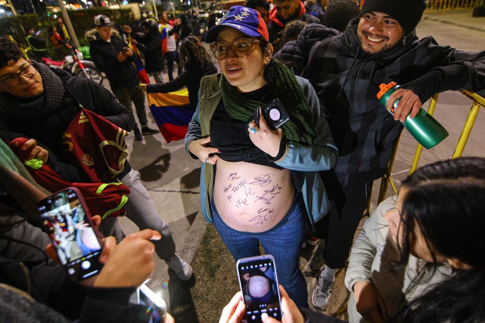 Una mujer muestra su barriga de embarazada firmada por varios integrantes de la selección de Venezuela durante el recibimiento este lunes, frente al Hotel Hilton Garden en Montevideo 