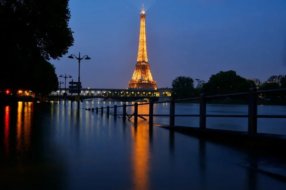 Una fotografía nocturna de la Torre Eiffel y la crecida del Sena en París.
